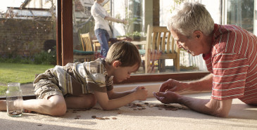 Grandparent and grandchild on floor counting coins