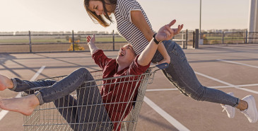 Friends pushing each other in shopping cart trolley