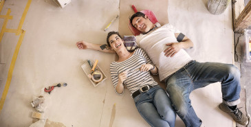 Couple taking a break from painting home and laughing on floor