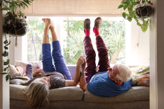 Old couple lying on their backs on the couch with feet in the air