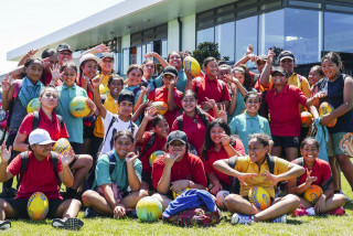 Group of children smiling and waving to camera