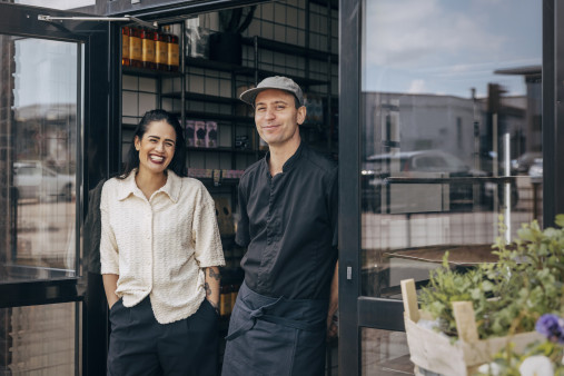 Happy Female Owner Standing With Male Colleague At Cafe Doorway