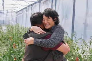 Two people hugging inside a greenhouse