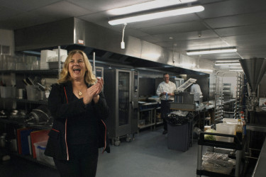 Woman claps her hands while standing in a commercial kitchen