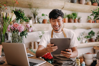 Florist shop worker looks at his tablet.