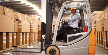 Man in hard hat driving a forklift in a warehouse