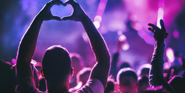 Person in a music concert crowd showing heart sign with hands