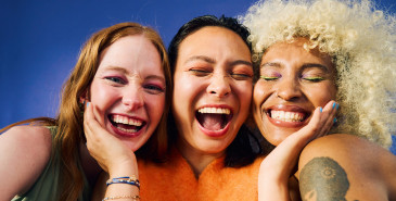 Three young women standing close together and smiling