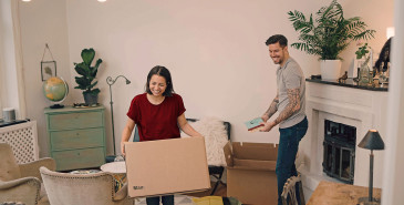 Couple moving boxes in new living room.