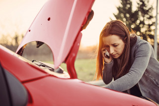 Person with car hood up calling for help on phone.