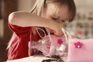 Child adding coin to her moneybox.