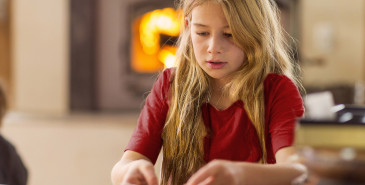 Child counting out play money on a table.