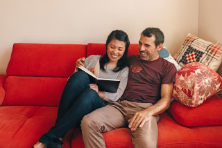 Couple sitting on couch reading notes happily