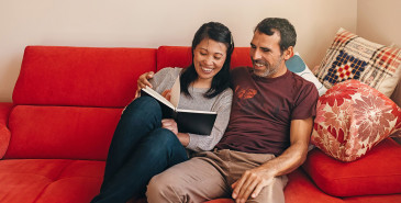 Couple sitting on couch reading notes happily