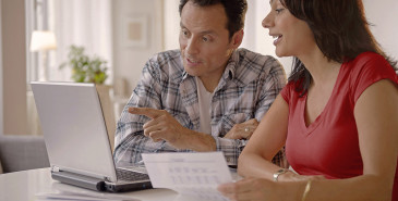 Couple discussing finances in front of laptop