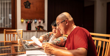 Couple doing paperwork together at home using laptop