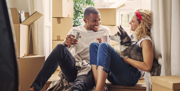 Couple drinking tea among moving boxes in new home