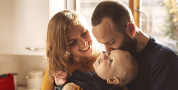 Young family with small infant smiling in kitchen