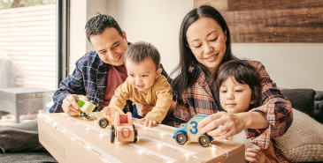 Family with two children playing with toy racing cars