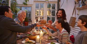 Extended family sitting at dinner table sharing plates