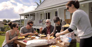 Family eating fish and chips takeout in garden