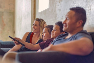 Family on sofa watching TV together