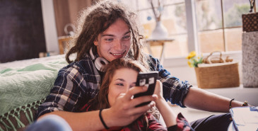 Friends sitting on floor of room reading smartphone screen