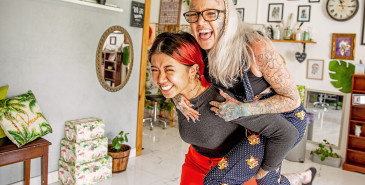 Couple playing piggy back in living room