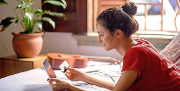 Person laying on bed shopping online with credit cards