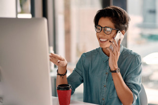 Person sitting in office and talking on mobile while using their computer