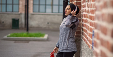 Person leaning against wall listening to music