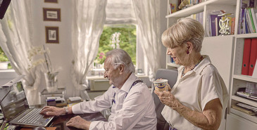 Senior person watching partner use laptop