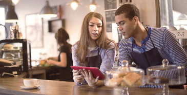 Two cafe staff looking at tablet computer