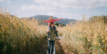 Father Carrying Child On Shoulders In Autumn