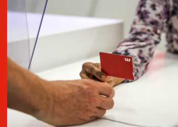 A man receives an eftpos card from a bank teller