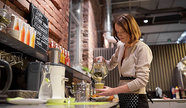 Woman working in a cafe pouring a drink.